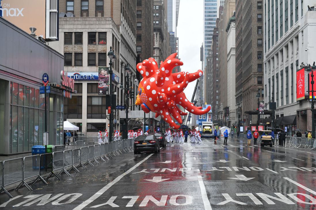 The Yayoi Kusama balloon is seen from a distance crossing the street